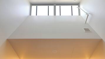 A modern, minimalist room with a large window, a desk, and a chair.