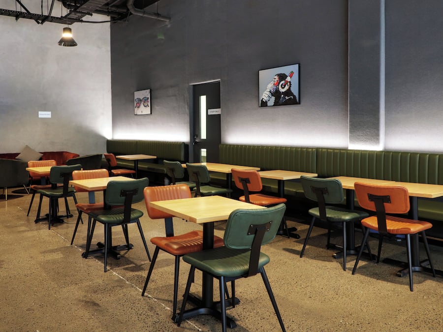 Interior de un restaurante con cabinas y mesas, algunas con sillas, y una pared con una puerta que dice 'STAFF ONLY'.