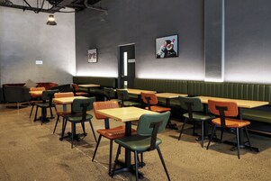 A restaurant interior with booths and tables, some with chairs, and a wall with a door labeled 'STAFF ONLY'.