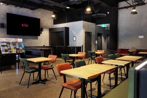 A modern restaurant with a flat-screen TV displaying 'VisitorPoint' and a sign for 'The Hotel IV'. - The Viv Hotel Wellington (Wellington)