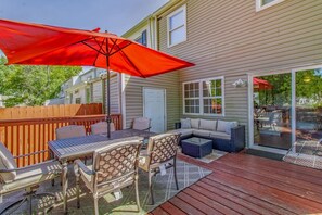 Eine Terrasse mit Tisch und Stühlen, einem roten Sonnenschirm und einem Holzdeck.