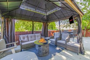 A covered outdoor seating area with a fire pit, wicker furniture, and a Netflix sign.