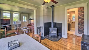 Un salón amplio con chimenea, suelo de madera y ventilador de techo.