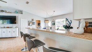 Una cocina moderna con barra, armarios blancos y un amplio ventanal.