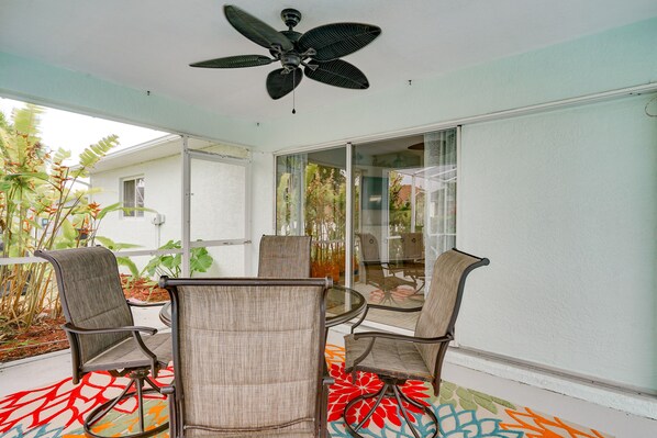 A room with a ceiling fan, a glass table, and four chairs.