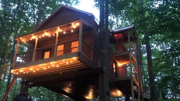 A wooden cabin with a balcony, surrounded by trees.