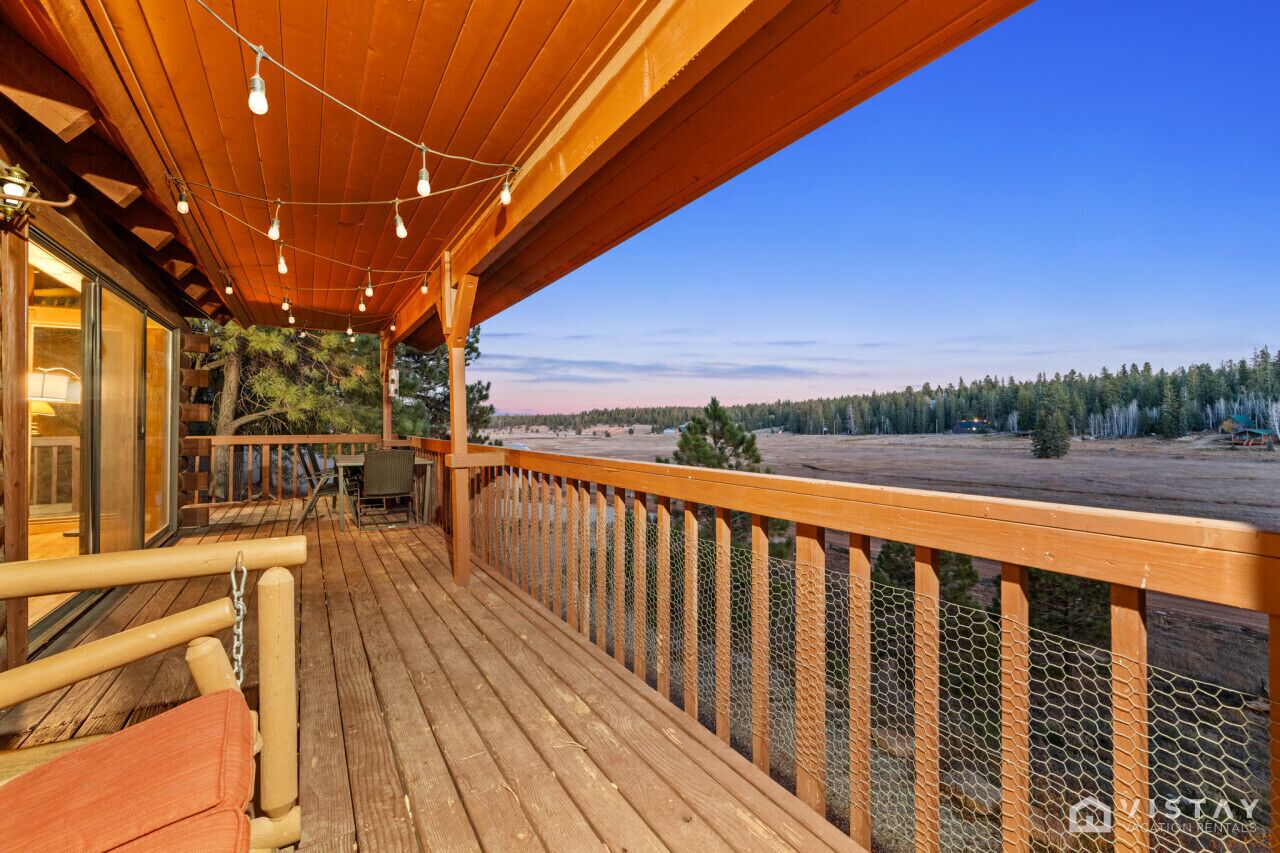 A wooden deck with a view of a forest and a body of water.