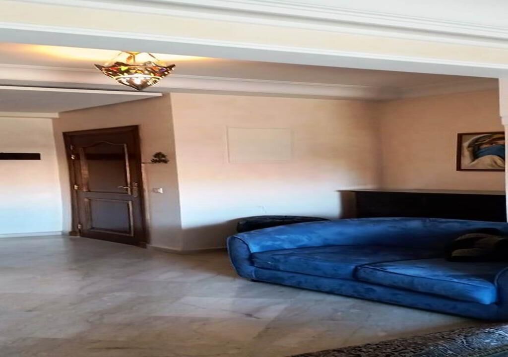 A living room with a blue sofa, a fireplace, and a chandelier.