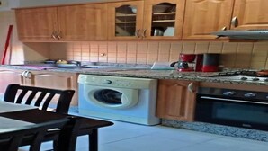 Una cucina con mobili in legno, una lavatrice, un fornello e un tavolo da pranzo con sedie.