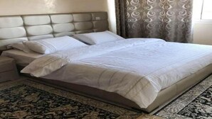 Un letto rifatto con cura, una comodino e un tappeto decorativo sul pavimento.