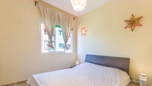 A bedroom with a bed, curtains, a star-shaped wall decoration, and a bedside lamp. - Residence Bouroud Hivernage 5376 (Marrakech)