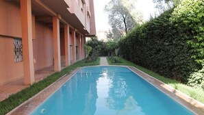 A swimming pool with a clear view of the surrounding greenery and a building with a simple architectural design. - Residence Bouroud Hivernage 5376 (Marrakech)
