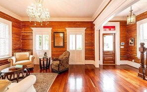 Ein geräumiges Wohnzimmer mit Holzvertäfelung, einem Chandelier und einem Kamin.