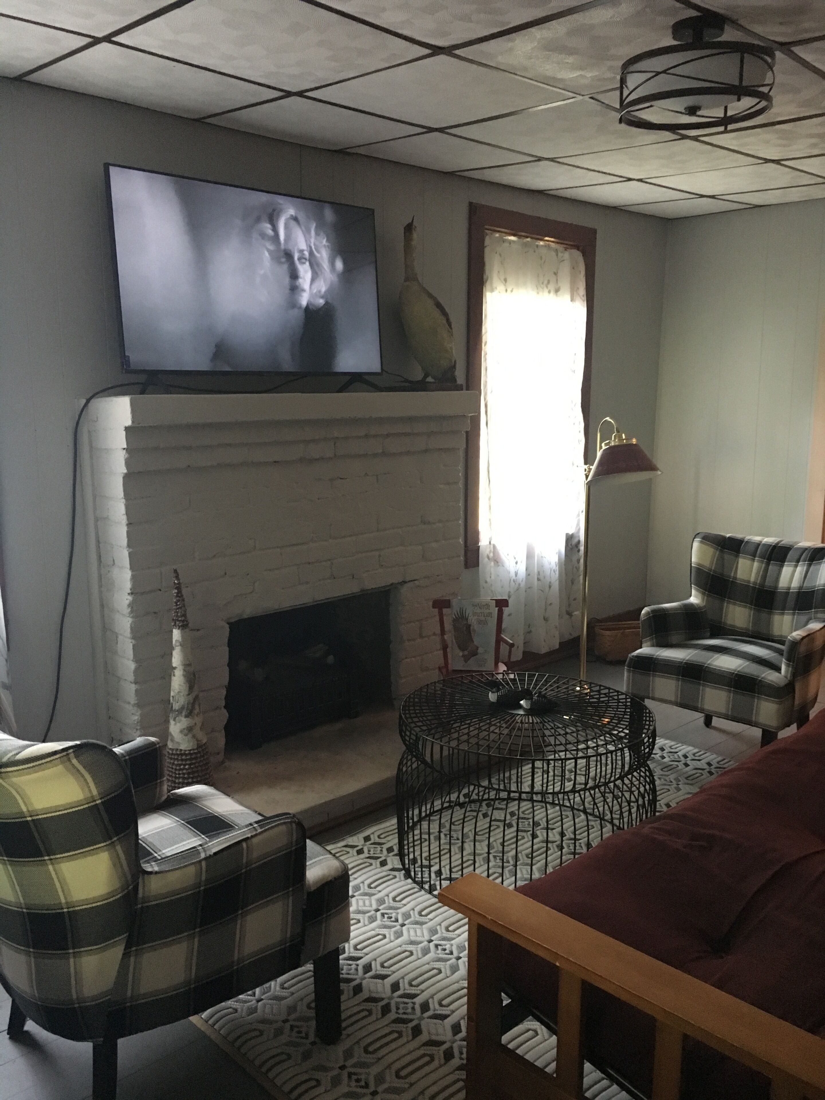 A living room with a fireplace, a television, and plaid furniture.