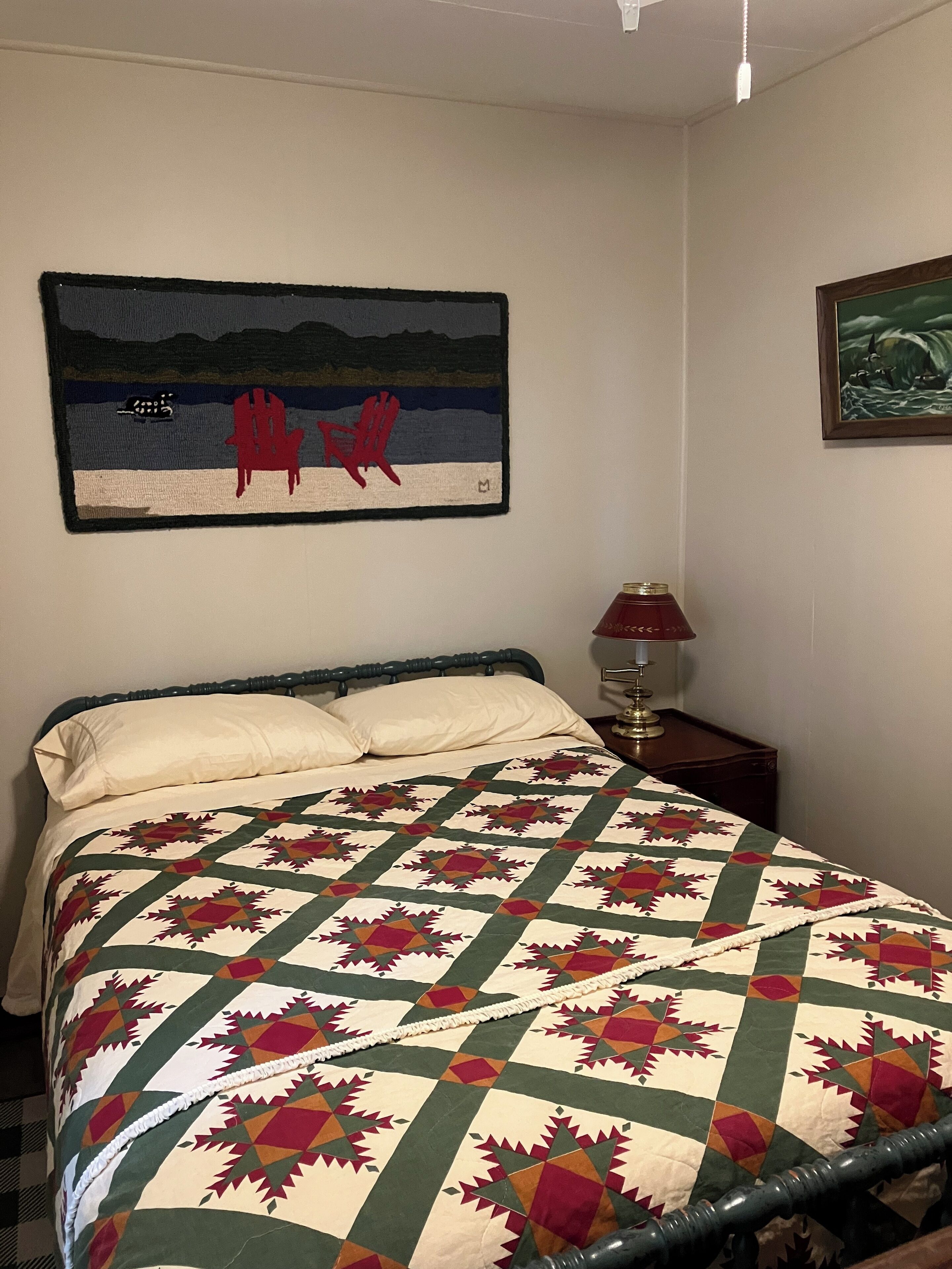 Een slaapkamer met een bed, nachtkastje, lamp en twee decoratieve wandobjecten.