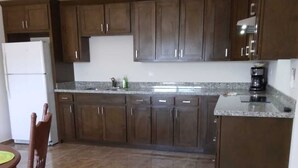 A kitchen with dark wooden cabinets, a granite countertop, and a tiled floor. - Downtown Oasis: Charming Two-Story Home in the Heart of Puerto Penasco, Mexico!  (Puerto Peñasco)