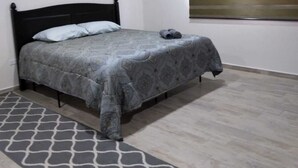 A bedroom with a bed, a patterned bedspread, a grey rug, and a window with blinds. - Downtown Oasis: Charming Two-Story Home in the Heart of Puerto Penasco, Mexico!  (Puerto Peñasco)