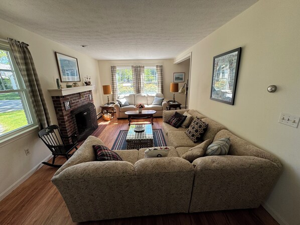 A living room with a fireplace, a sofa, a coffee table, and a view of the outdoors. - Goose Rocks Beach Family Vacation House ! (Kennebunkport)