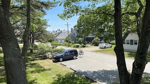 En bostadsgata med hus, en parkerad blå SUV och en vit bil.