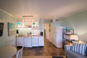 Una cocina funcional con electrodomésticos blancos, una mesa de comedor y un sofá.