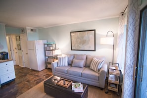 A living room with a sofa, coffee table, lamp, and a framed map on the wall.