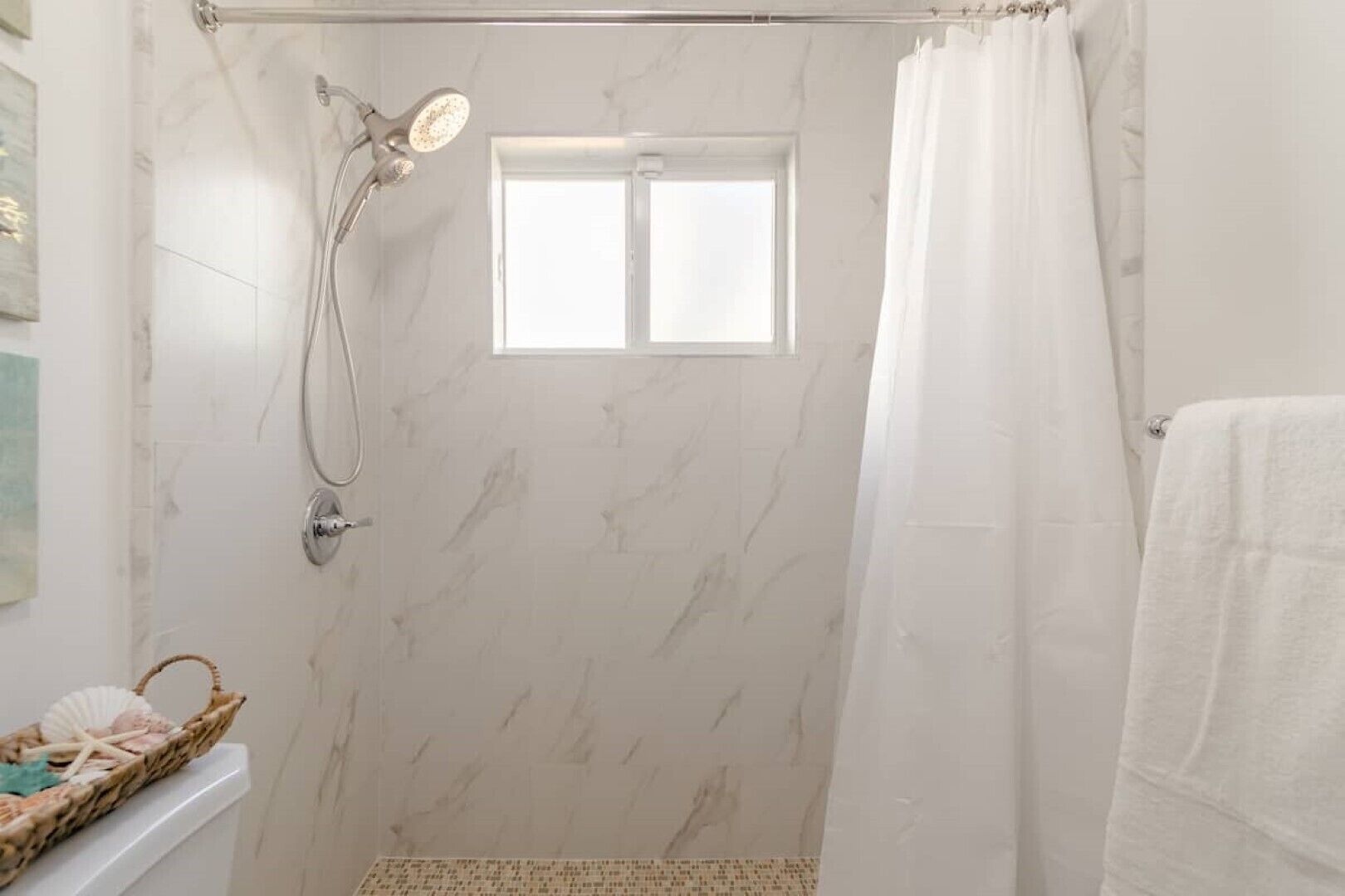 A bathroom with a shower, a window, and a towel rack.