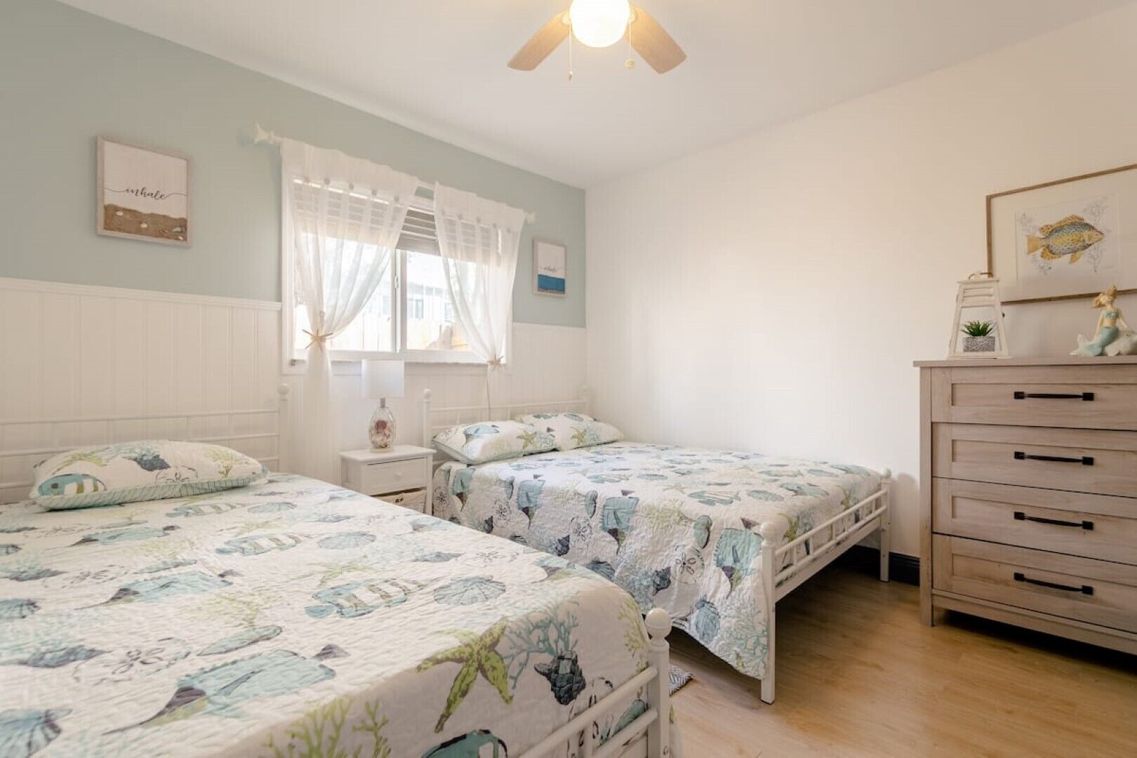 Un dormitorio con dos camas, un aparador y un ventilador de techo.