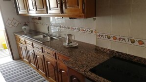 A kitchen with wooden cabinets, a granite countertop, a stove, and a tiled backsplash.