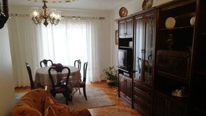 A living room with a dining table, chairs, a sofa, a cabinet, and a chandelier.