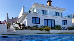 Ein modernes, zweistöckiges Haus mit einem Schwimmbad im Vordergrund.