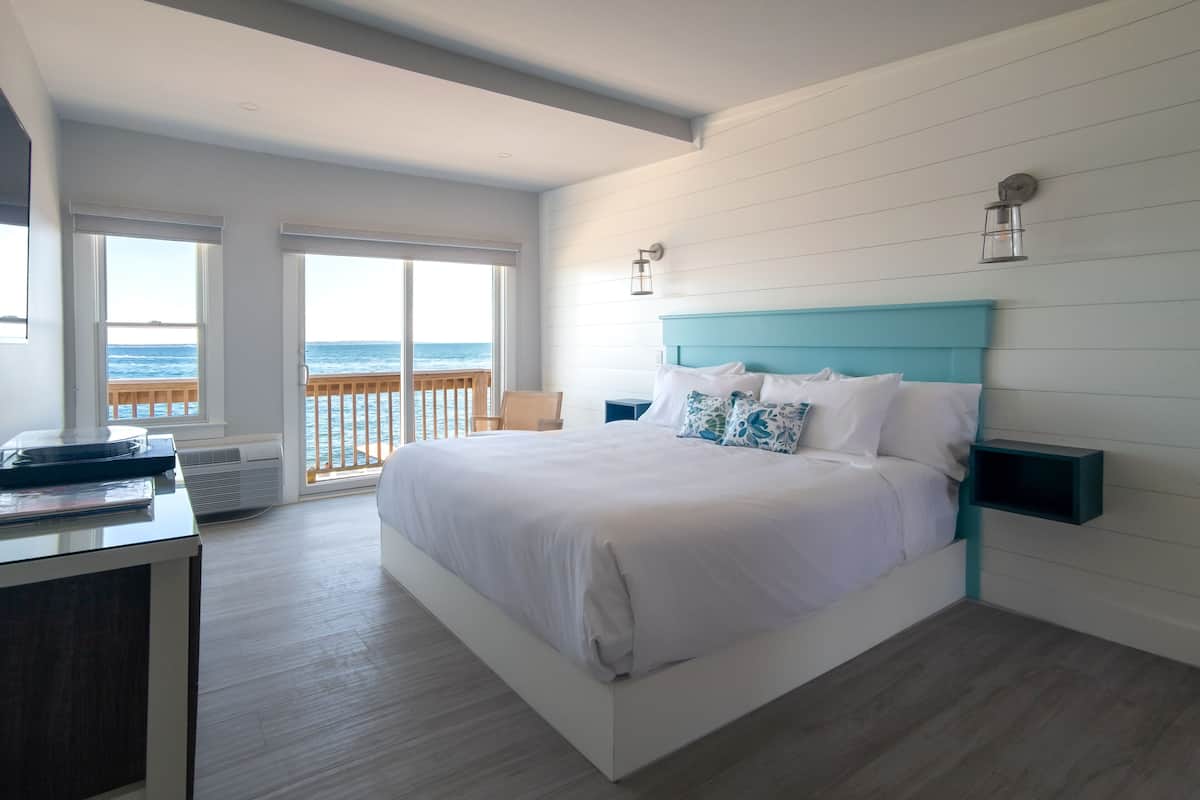 Un dormitorio con una cama grande, un escritorio y vista al océano.