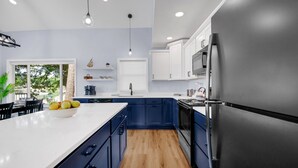 A modern kitchen with blue cabinets, a white countertop, and stainless steel appliances. - Pearl Beach:  Dive into Summer Fun at Pearl Beach – Swim, Kayak & Relax! (Greenville)