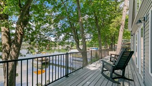 A wooden deck with a black railing, overlooking a calm body of water and trees. - Pearl Beach:  Dive into Summer Fun at Pearl Beach – Swim, Kayak & Relax! (Greenville)
