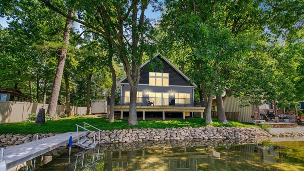 A house with a deck, surrounded by trees and a pond. - Pearl Beach:  Dive into Summer Fun at Pearl Beach – Swim, Kayak & Relax! (Greenville)