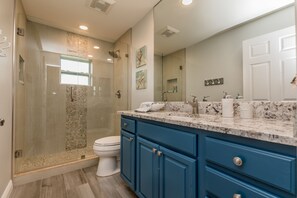 Ein modernes Badezimmer mit einer Duschkabine aus Glas, einer weißen Toilette und blauen Schränken.