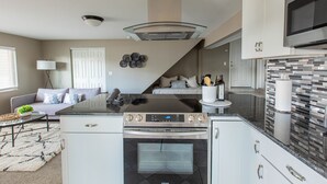 A modern kitchen with a built-in oven, microwave, and stainless steel range hood. - NEW Renovated Guest Suite | 30 min to DIA & DEN (Brighton)