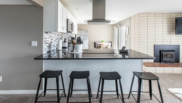 A modern kitchen with a central island, black bar stools, and a fireplace. - NEW Renovated Guest Suite | 30 min to DIA & DEN (Brighton)
