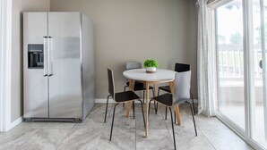 A modern kitchen with a stainless steel refrigerator, a round dining table with four chairs, and a potted plant. - NEW Renovated Guest Suite | 30 min to DIA & DEN (Brighton)