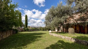 A well-maintained garden with a stone wall, a variety of trees, and a clear blue sky. - Appartamento Ciliegia in Tuscan Hills with Shared Pool, Roccastrada, Italy (Roccastrada)