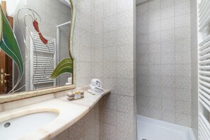 Ein Badezimmer mit Waschbecken, Spiegel, Handtuchhalter und Duschbereich.