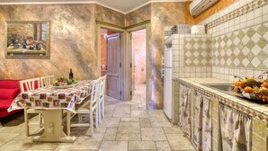 A narrow kitchen with a dining table set for two, a red chair, and a tiled backsplash. - Appartamento Uva shared pool, Roccastrada, Italy (Roccastrada)