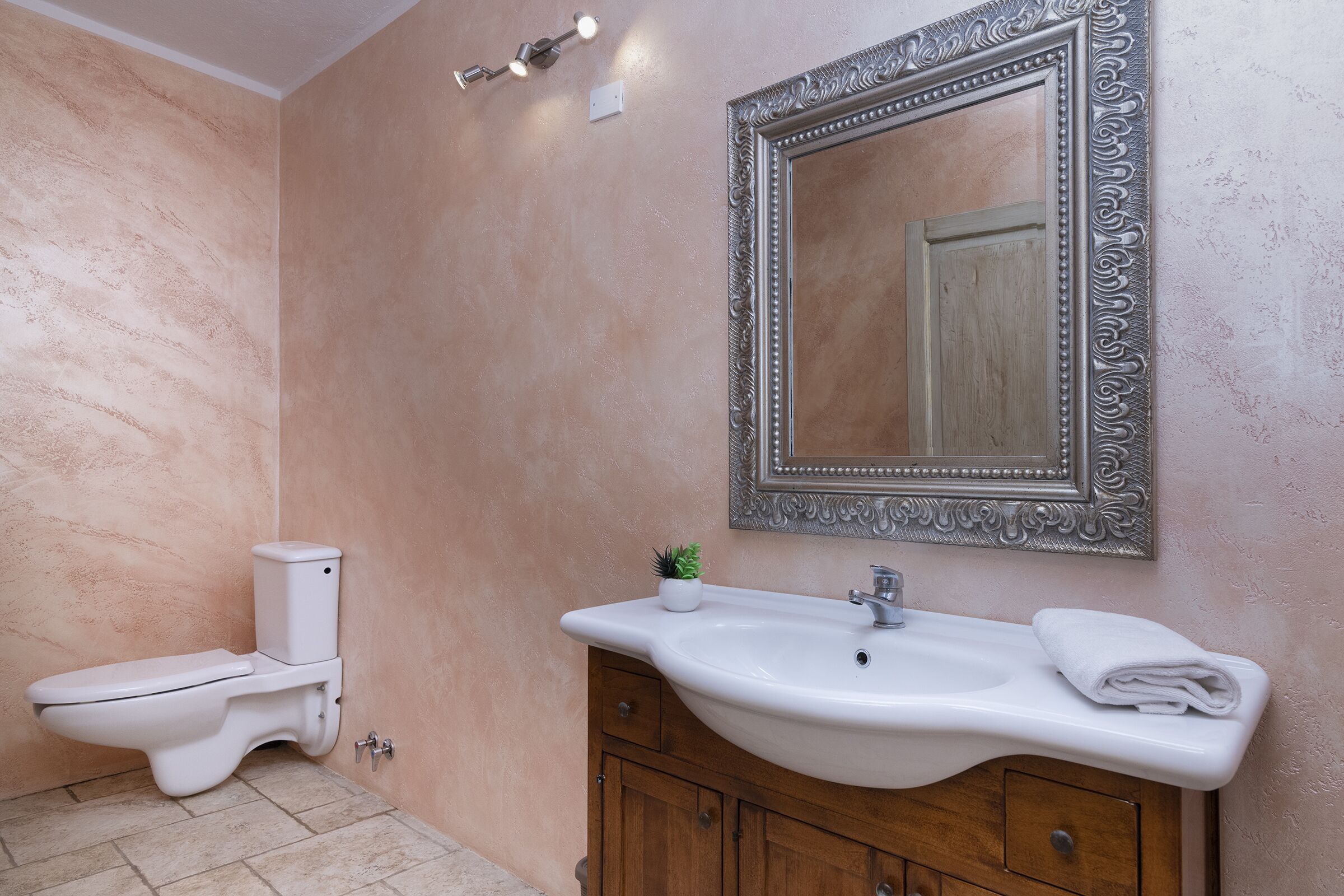 A bathroom with a toilet, sink, mirror, and cabinet.