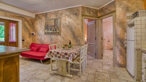 A kitchen with a dining table, a red sofa, a painting on the wall, and a refrigerator. - Appartamento Uva shared pool, Roccastrada, Italy (Roccastrada)