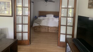 A bedroom with a wooden bed, a ceiling fan, and a television.