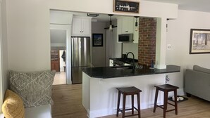 A modern kitchen with a central island, stainless steel appliances, and a brick accent wall.