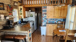 Une cuisine spacieuse avec des meubles de rangement en bois, un coin repas avec une table et des chaises en bois, et un canapé gris.