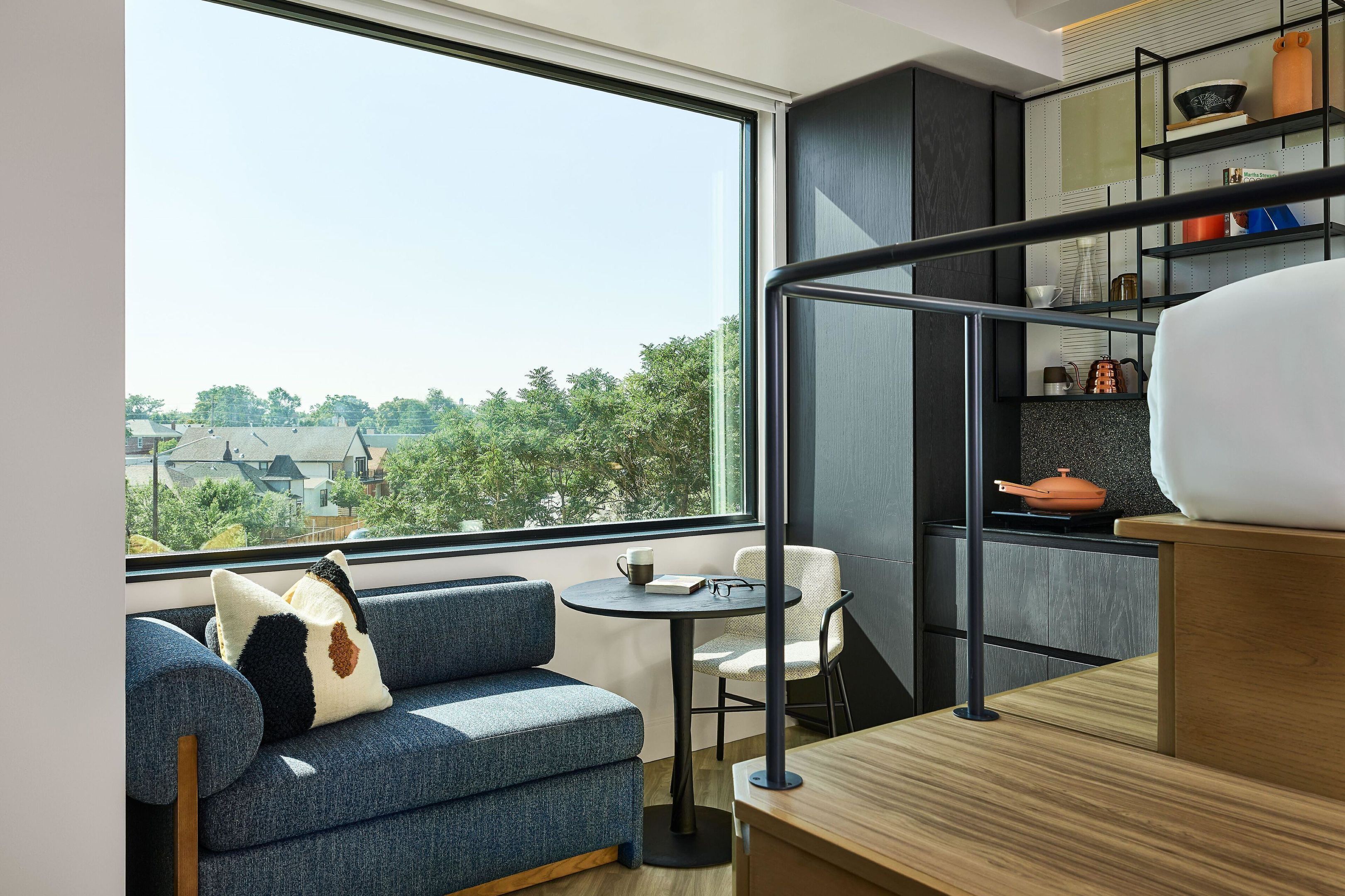 A modern interior with a sofa, a small table, and a kitchen area with shelves.