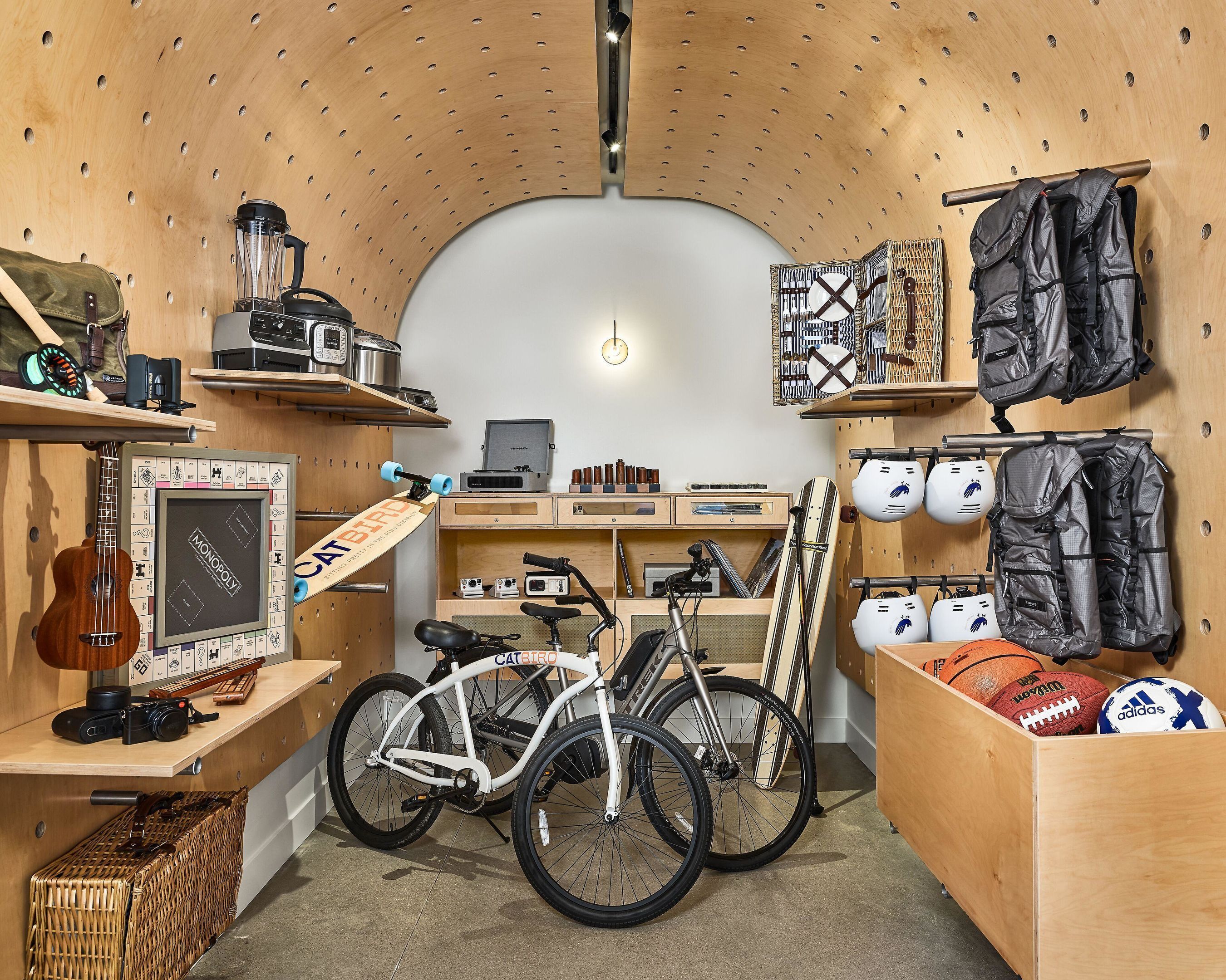 A compact room with a wooden ceiling, a bicycle, a guitar, and various sports balls.