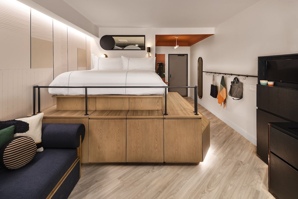 A modern bedroom with a bed, built-in wardrobe, and a seating area.
