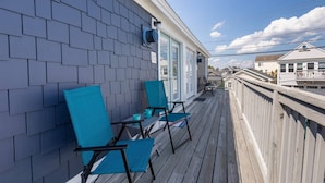 Una terraza de madera con dos sillas azules y una mesa, con vista a una zona residencial.